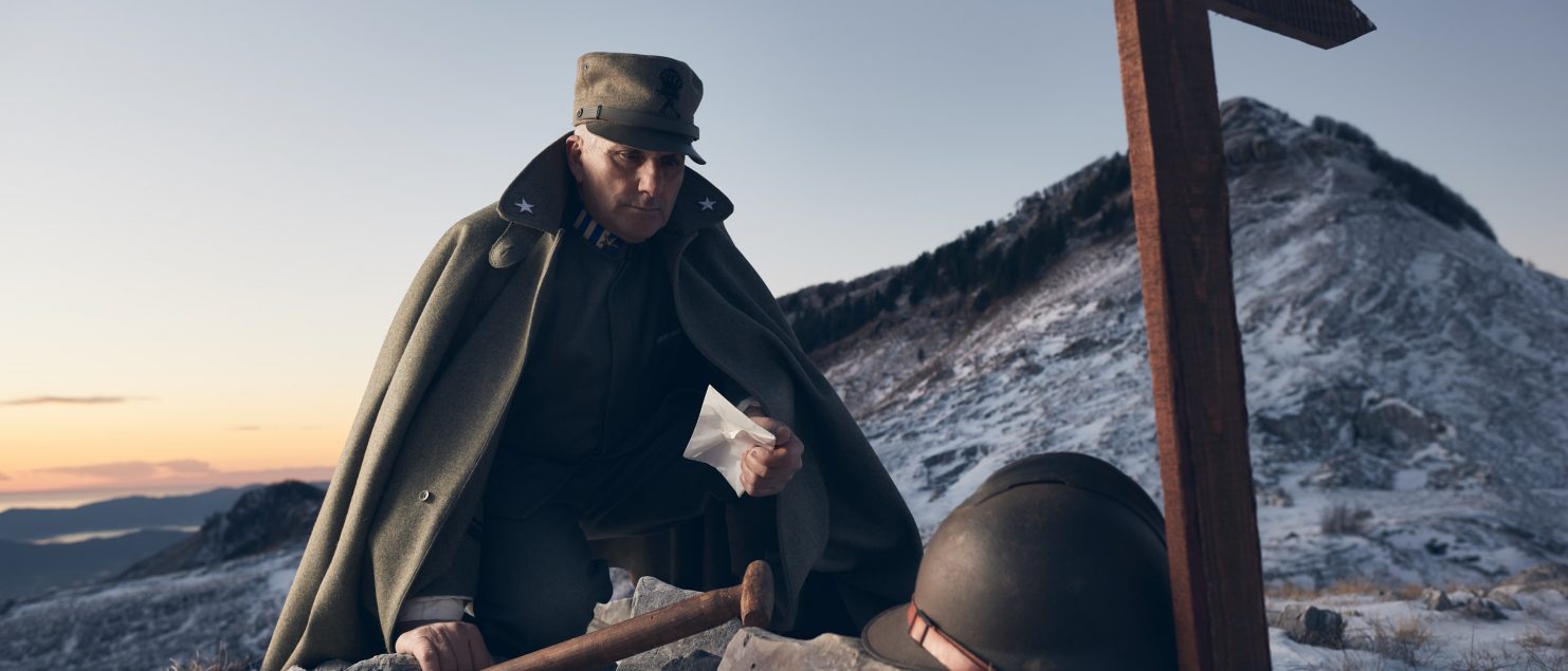 Portrait of Alberto Simonelli wearing a World War I Italian Infantry Man Uniform. Image shot on Monte Sagro, Tuscany, Italy showing Alberto looking a a cross and army helmet surrounded by swan during sunset.Personal project dedicated to historic portraits. Image series by David Umberto Zappa - portrait, commercial and advertising photographer. Ritratto di Alberto Simonelli, in uniforme militare Mitragliere Italiano Prima Guerra Mondiale. Immagine scattata sul Monte Sagro, Toscana. Alberto chino su una croce ed elmetto circondato da neve sotto le luci del tramonto. Progetto personale del fotografo commerciale, pubblicitario, ritrattista ed editoriale David Umberto Zappa.