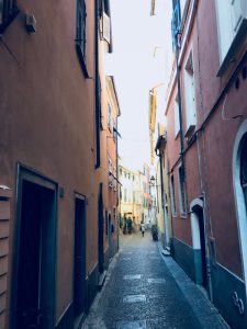 Via Rossi, Sarzana nel punto più stretto tra i palazzi color rosa e ocra con sanpietrini. Location Scout duzimage