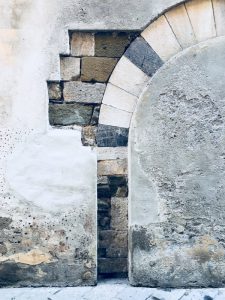 Sarzana, sezione di muro nel centro storico di Sarzana. Pietra incastonata nell'intonaco formante un arco. location scout italia - duzimage
