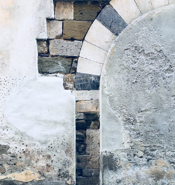 Sarzana, sezione di muro nel centro storico di Sarzana. Pietra incastonata nell'intonaco formante un arco. location scout italia - duzimage