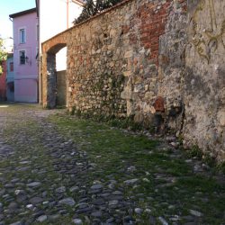 Via del Torrione Genovese Sarzana con pavimentazione antica in pietra, muri decadenti con pietra e mattoni a vista. Visuale in direzione nord. Location Scout duzimage