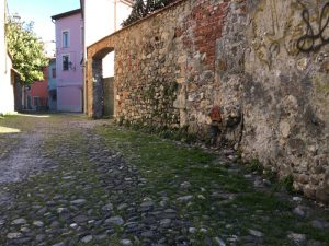 Via del Torrione Genovese Sarzana con pavimentazione antica in pietra, muri decadenti con pietra e mattoni a vista. Visuale in direzione nord. Location Scout duzimage