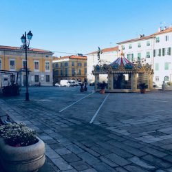 giostra in piazza Matteotti a Sarzana con pavimentazione lastricata e palazzo comunale sullo sfondo. location scout duzimage