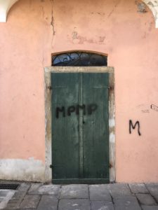 Via Torrione Genovese, Sarzana. Portone verde con graffity. Facciata rosa. Pavimento lastricato. Location Scout - duzimage