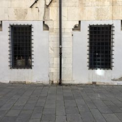 Piazza Matteotti Sarzana. Facciata con grandi finestre con inferiate. Cornice in marmo bianco e muro in pietra.