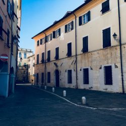 Piazza Matteotti Sarzana con facciate di palazzi storici e portici sul lato sinistro. Inferiate e portoni. Location Scout duzimage