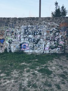muro sotto la circonvallazione di Sarzana. Pietra e graffity con suolo in erba e terra. Location scout duzimage