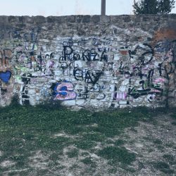 muro sotto la circonvallazione di Sarzana. Pietra e graffity con suolo in erba e terra. Location scout duzimage