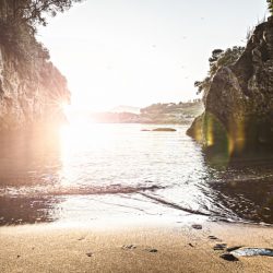 spiaggia privata tra la Caletta ed Eco del Mare vista al tramonto con riflesso del sole, scogli e gabbiani in volo. Location Scout Italia - duzimage