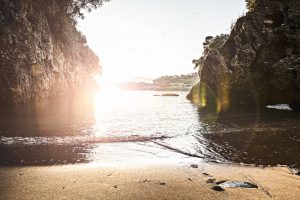 spiaggia privata tra la Caletta ed Eco del Mare vista al tramonto con riflesso del sole, scogli e gabbiani in volo. Location Scout Italia - duzimage