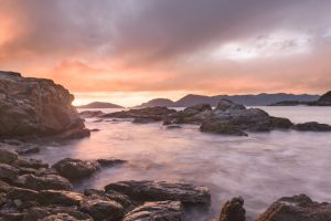 tramonto sul Golfo dei Poeti visto dagli scogli tra le due spiagge di Fiascherino. Scogli in primo piano ed acqua del mare tinta di viola. Cielo nuvoloso. Location scout italia - duzimage
