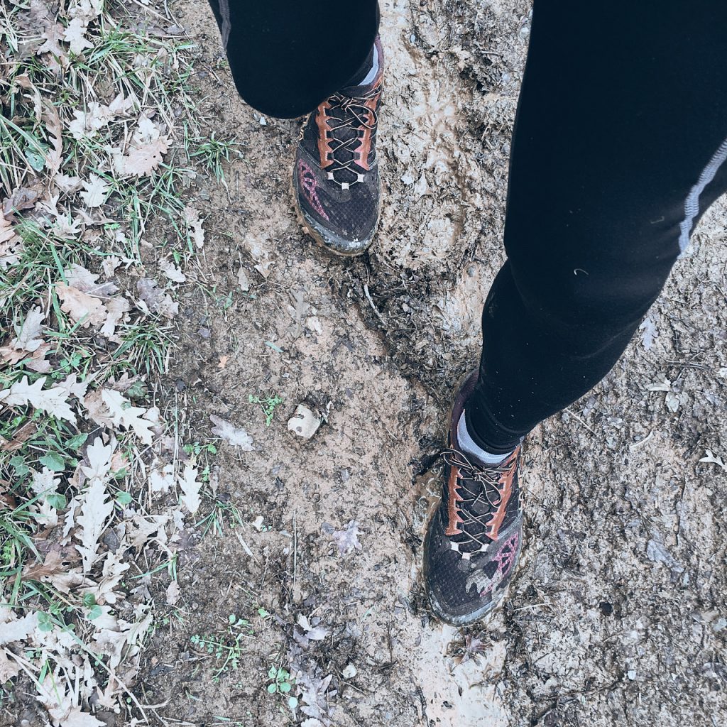 ripresa dall'alto verso il basso di un paio di piedi con scarpe da running nel fango