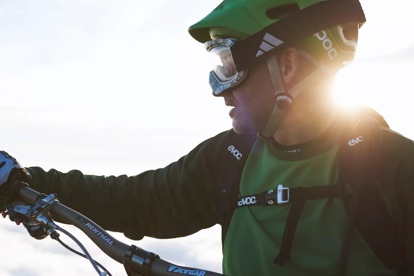 Portfolio sport & lifestyle del fotografo duzimage - uomo biker MTB con casco e maglia verde. Luce del sole dietro la nuca. Manubrio semi visibile